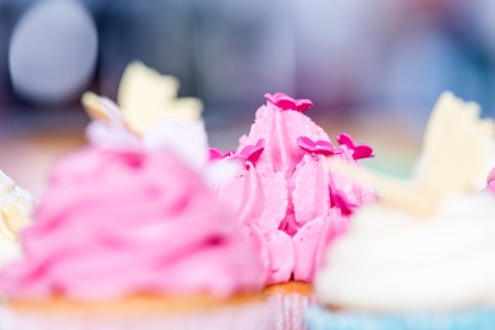 Detailed view of decorative icing on cupcakes with twirled frosting sprinkled with little pink flowersの写真素材