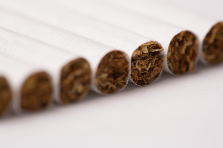 Oblique row of cigarettes with tobacco texture at the tips with selective focus to one in the row and copyspaceの写真素材