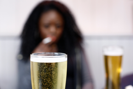 African woman drinking beer in a pub with focus to the cold glass of ale in the foregroundの写真素材