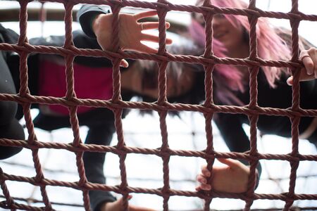 Low Angle View of Two Teenage Girls Having Fun and Playing on Jungle Gym as seen from Belowの写真素材
