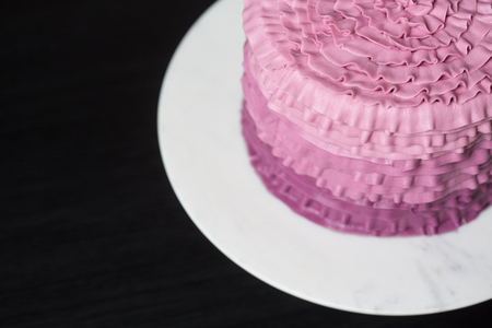 Pink cake in a white plate on a black tableの写真素材