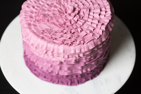Close up shot of pink cake in a white plate on black background