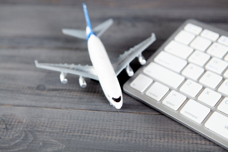 plane and keyboard. online purchase of airline tickets on a gray wooden tableの写真素材