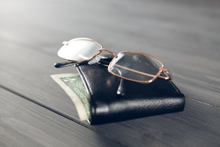 wallet and glasses on a gray wooden table