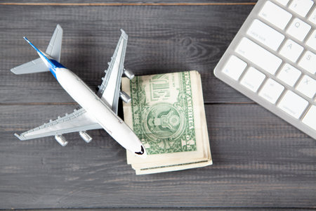 plane, money and keyboard. online purchase of airline tickets on a gray wooden tableの写真素材