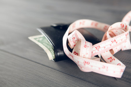 measuring tape and wallet on a gray wooden table. amount of moneyの写真素材