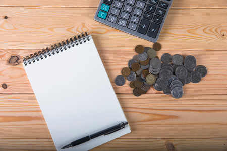 calculator, coins, notepad and pen on the tableの写真素材