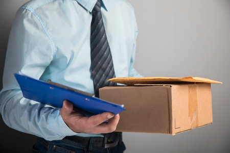 courier holding parcel and papers on gray background