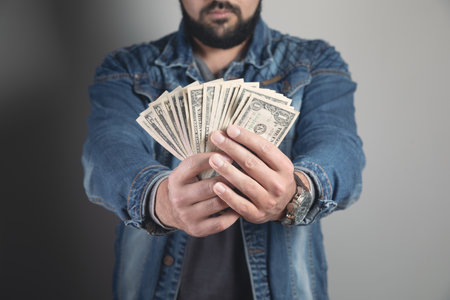 man holds wads of money and shows