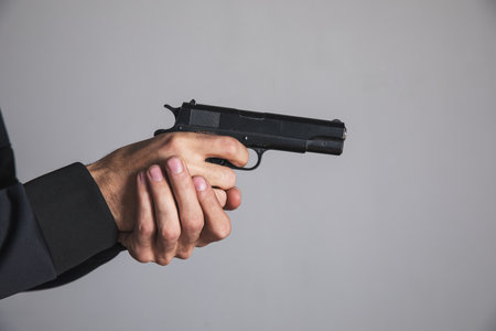 a man holding a black pistol in his hand threateningの写真素材