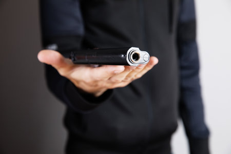 a man holding a black pistol in his hand threateningの写真素材