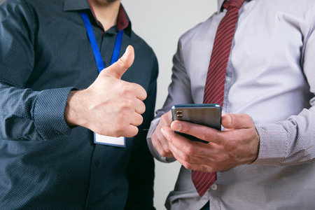 workers look at the phone and show their thumbs up .の写真素材