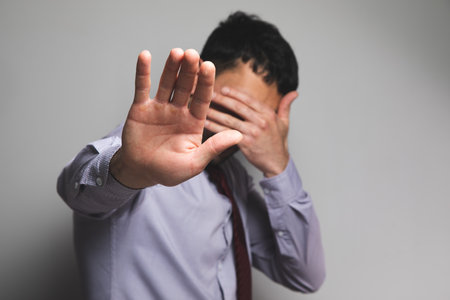 man covers his face on a gray background .