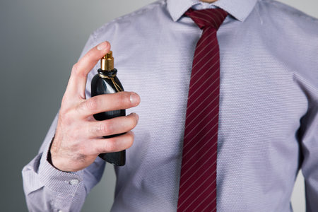 man sprinkles perfume on gray background .の写真素材