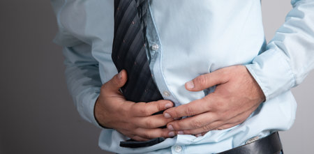 a man has a stomach ache on a gray background