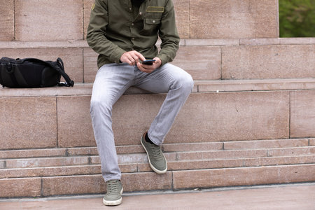 a young guy on the street sits on the phoneの写真素材