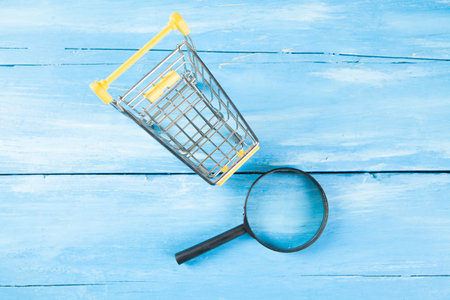 magnifier and basket. shopping search concept. on a blue wooden backgroundの写真素材