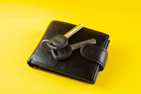 keys and black wallet on a yellow background