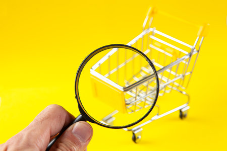magnifier and basket. shopping search concept. on a yellow backgroundの写真素材