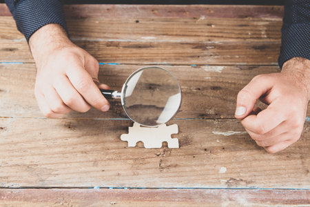 magnifying glass examines puzzle piecesの写真素材