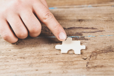 man holding puzzle piece on wooden backgroundの写真素材