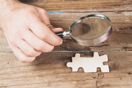 magnifying glass examines puzzle piecesの写真素材