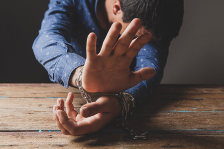 prisoner in chains covers his faceの写真素材