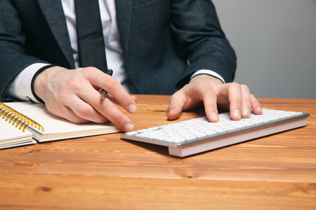a man in a suit writes on a keyboard on a gray background