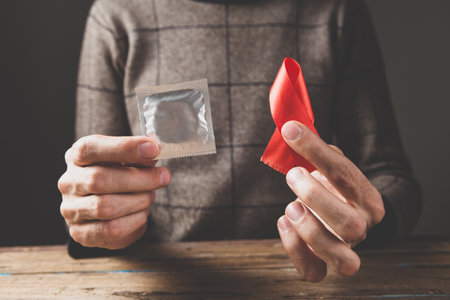 holding a red ribbon and a condom