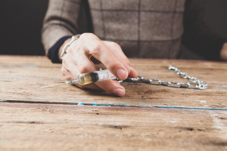 a man in handcuffs holding a syringeの写真素材