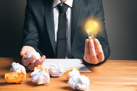 man holding glowing lamp and wad of paper on gray backgroundの写真素材