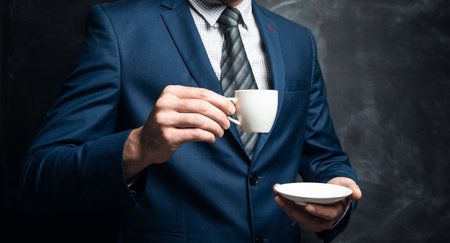 businessman holding a cup of coffee on a dark backgroundの写真素材