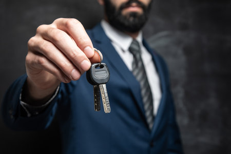 businessman holding keys on dark backgroundの写真素材