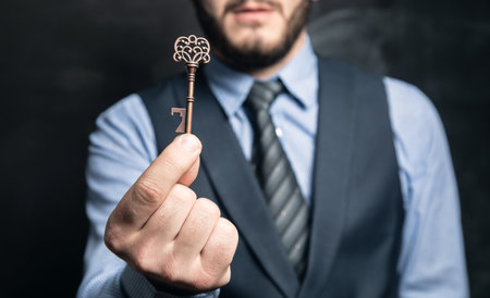 businessman holding keys in hand on black backgroundの写真素材