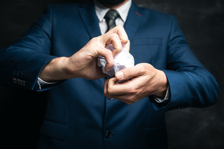 young businessman squeezed paper in hand on dark backgroundの写真素材