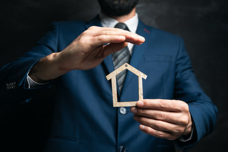 businessman holding a house on a dark backgroundの写真素材