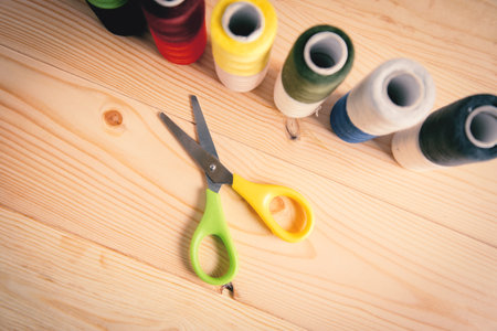 multi colored threads and scissors on wooden backgroundの写真素材