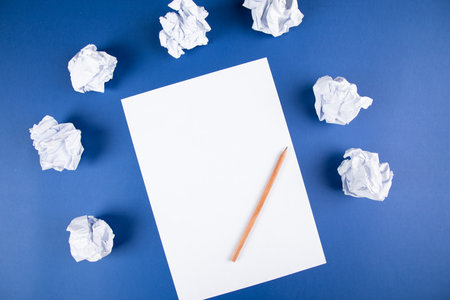 paper with pencil and wads of papers on a blue backgroundの写真素材