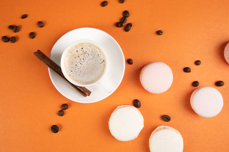 white macarons and coffee with cinnamon on an orange background. coffee seedsの写真素材
