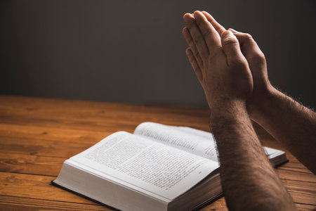 a man praying on a book on a dark background
