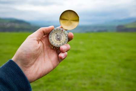 holding a compass on the background of a green field