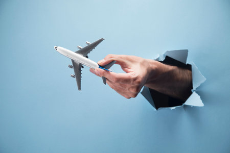 Man's hand holds an airplane on a blue backgroundの写真素材