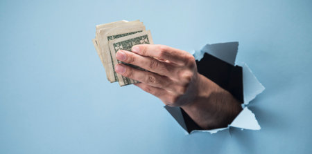 Man's hand holding money on blue backgroundの写真素材