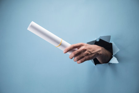 Man's hand holds papers on blue backgroundの写真素材