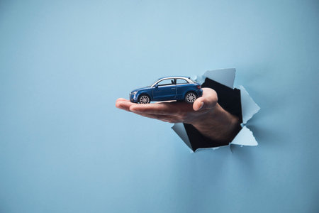 Man's hand holding a car on a blue backgroundの写真素材