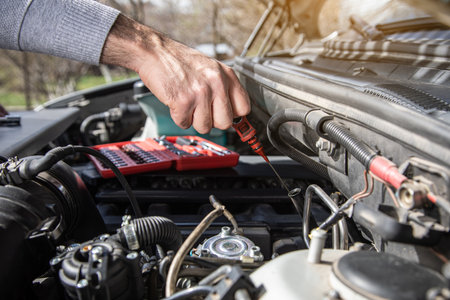 a man checks the oil of a car under the hoodの写真素材