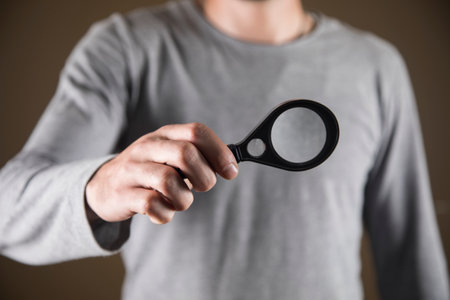 a man in gray holding a magnifying glassの写真素材