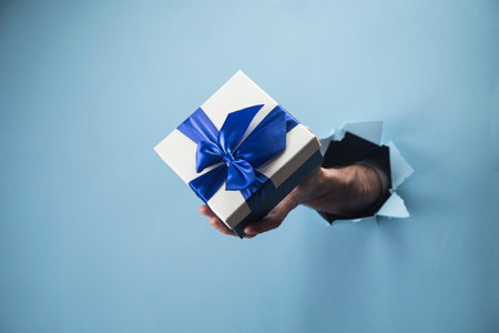 Male hand holding a gift on a blue background