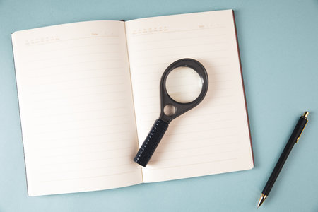 notebook, pen and magnifying glass on the table