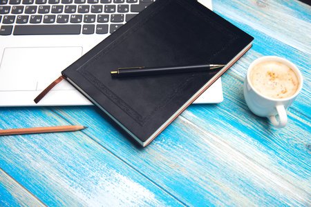on the table laptop, notepad, pen and coffee